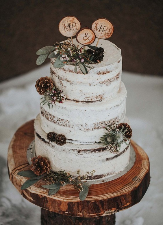 white wedding cake with greenery and pinecones for neutrals december wedding 2020