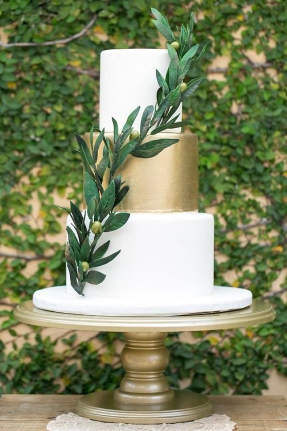 gold wedding cake with greenery and gold table stand for emerald and gold march wedding color 2021