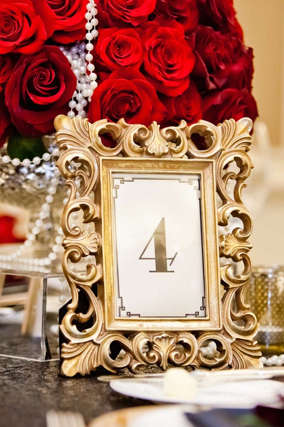 golden table number and red flowers for red and black wedding colors red black and gold