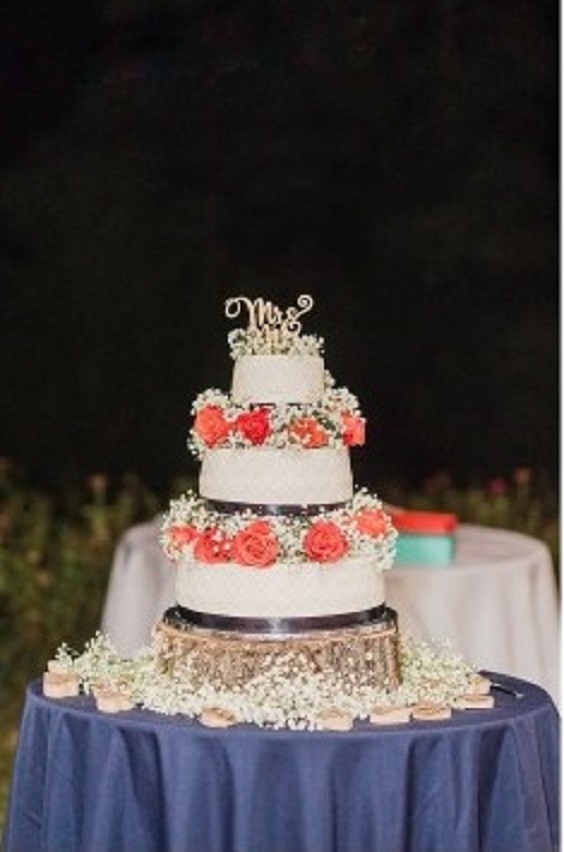 white wedding cake dotted with coral flowers in navy blue table cloth for navy blue and coral wedding color beach