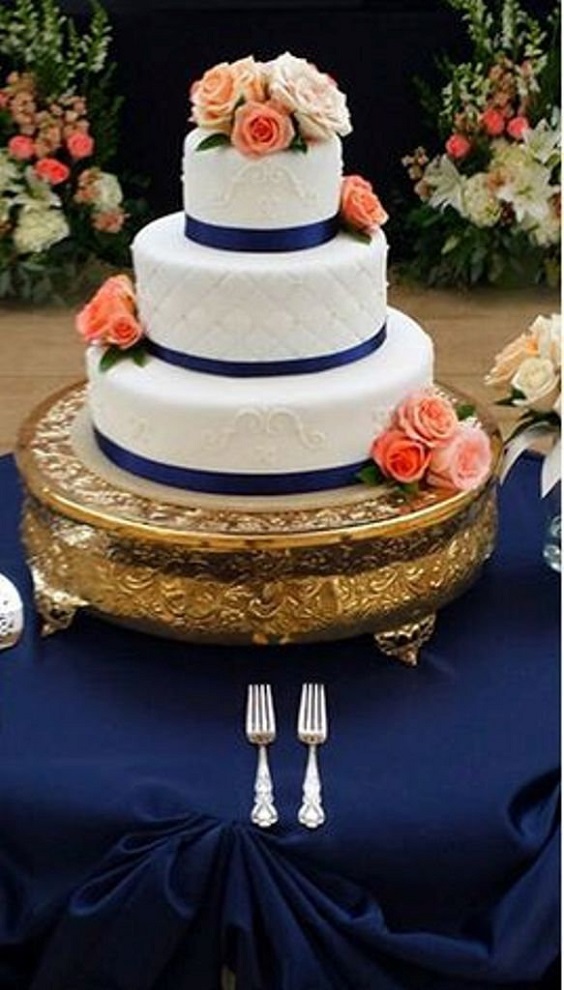 white wedding cake with gold cake stand coral flowers in navy tablecloth for navy blue and coral wedding color navy coral gold