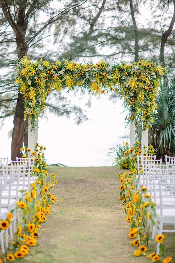 wedding chairs and ceremony arch with yellow and green flowers for yellow and green simple beach wedding