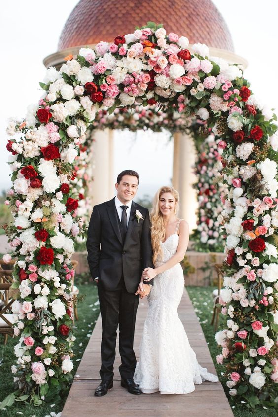 red and white wedding ceremony arch with greenery for beach red and white wedding