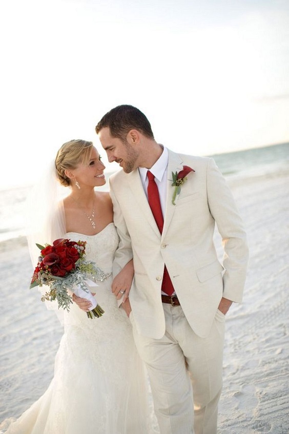 white wedding groom attire with red necktie and white bridal gown with red bouquets for romantic red and white wedding